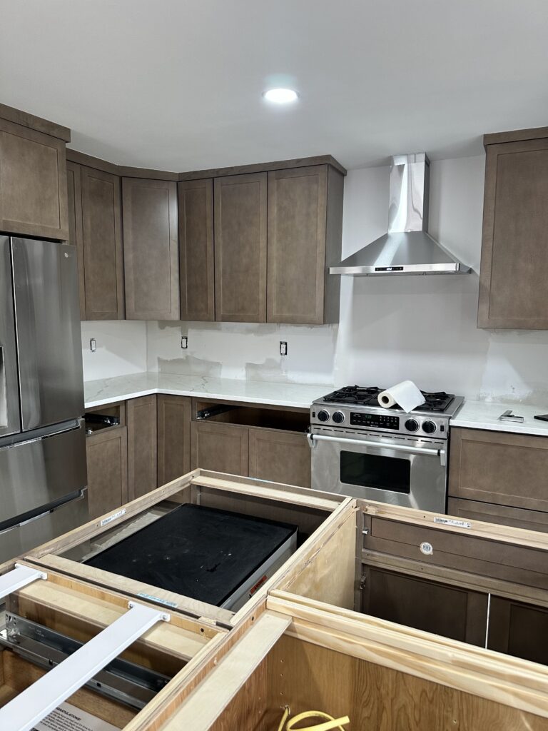 Kitchen island being built with quartz counters installed and stainless chimney hood