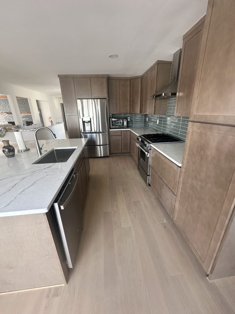 Galley view of a remodeled kitchen with light hardwood floors and stained shaker cabinets
