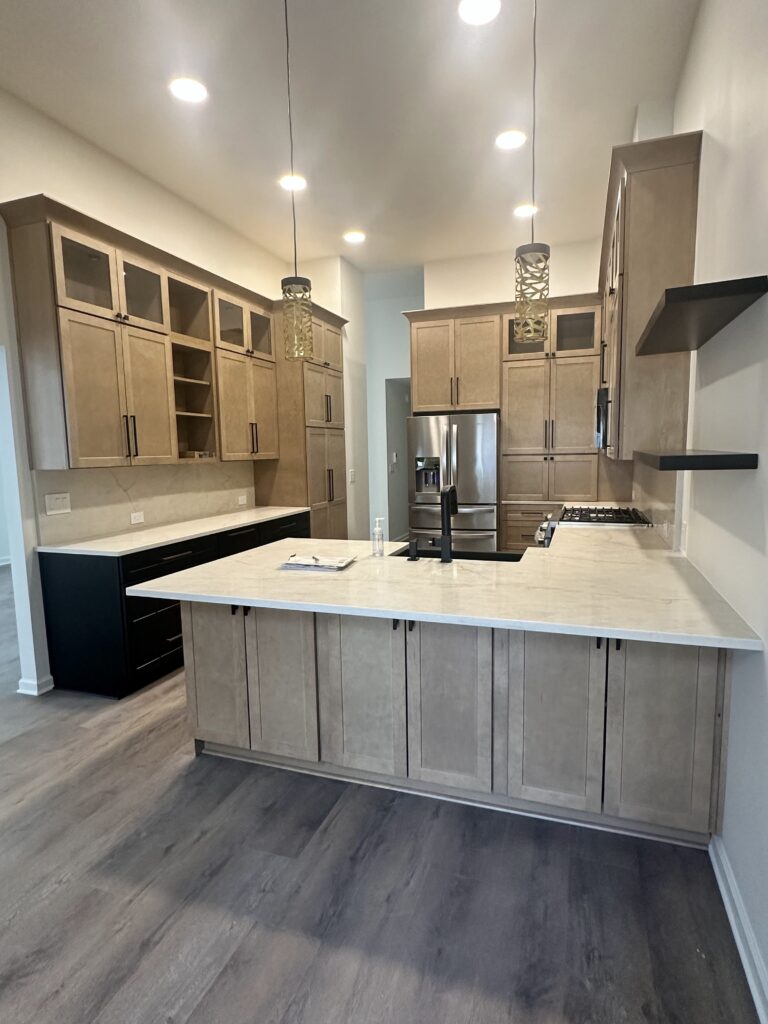 Quartz peninsula with gray-washed shaker cabinets and black base cabinets on the side counter