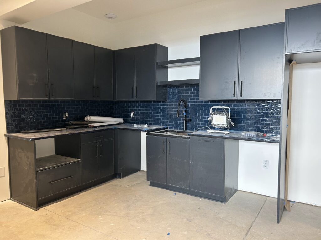 Navy shaker kitchen cabinets with a matching navy glass subway tile backsplash