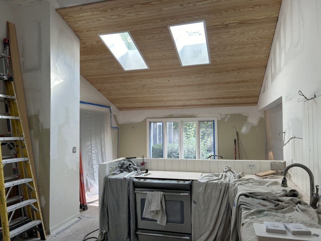 Before: vaulted kitchen with a knotty pine tongue-and-groove ceiling and two skylights