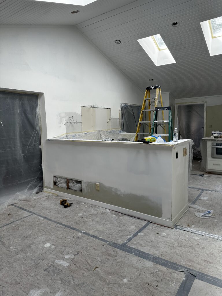 White vaulted ceiling with skylights and the peninsula wall patched and ready for paint