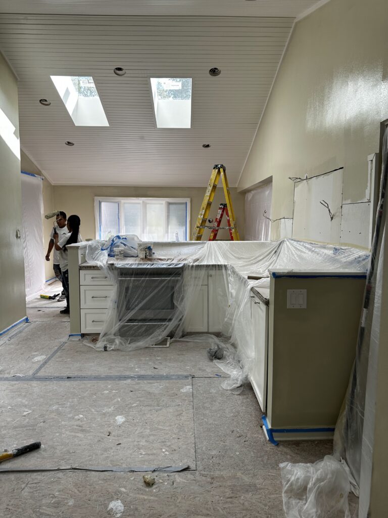 Kitchen walls freshly painted with cabinets and appliances masked in plastic